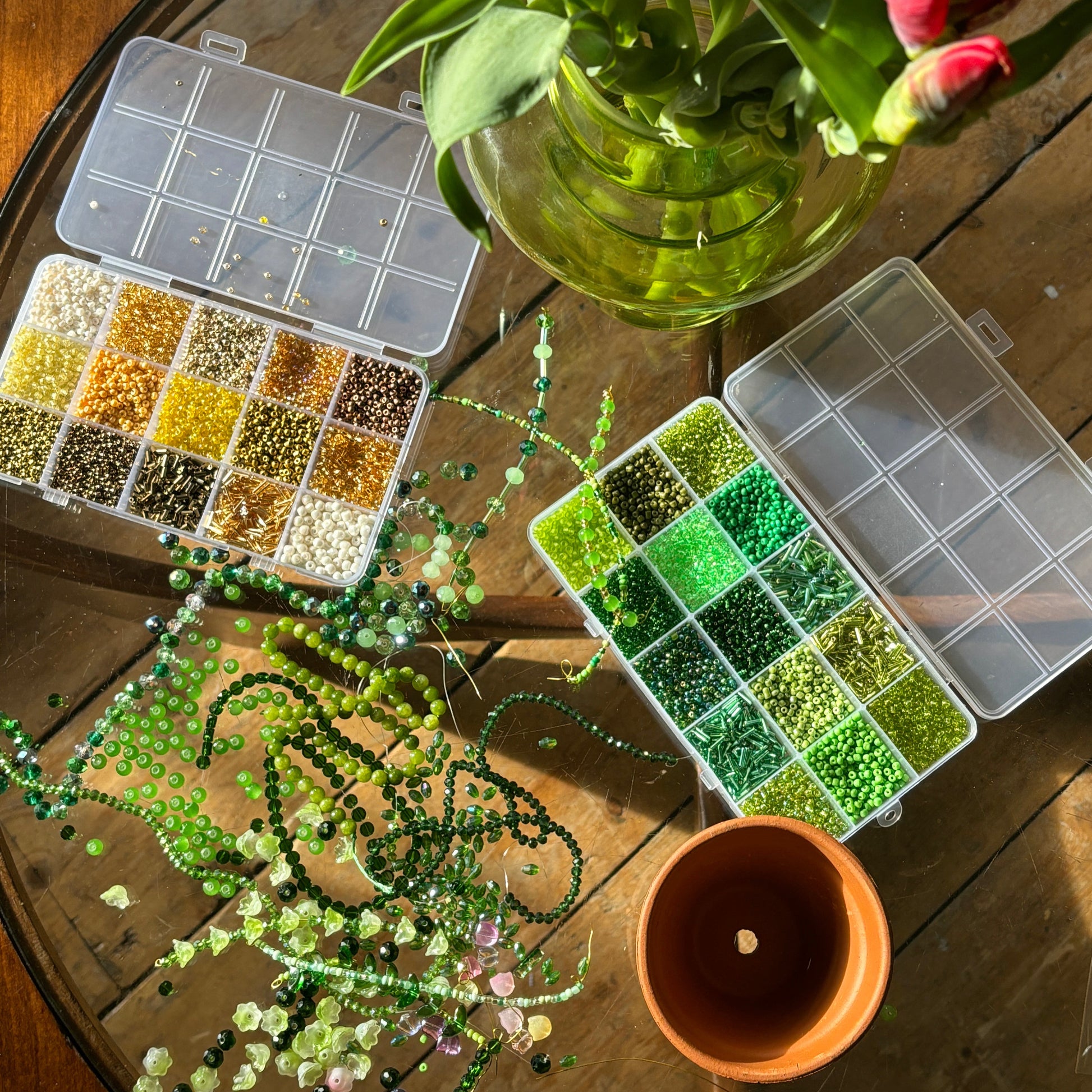 beads on the table beside tulips and green glass beads for making beaded plants
